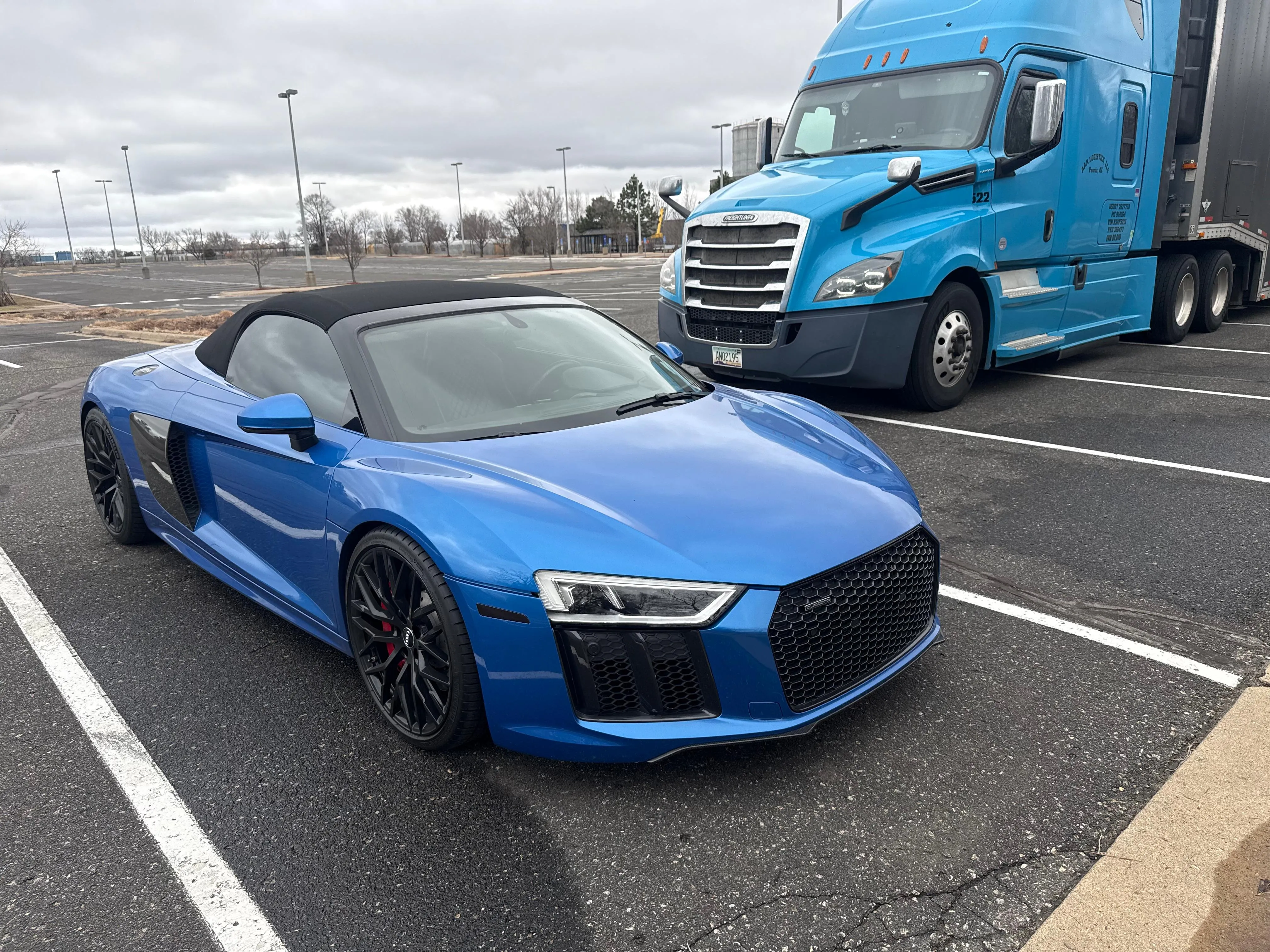 Blue Audi R8 Spyder parked next to our blue Freightliner semi-truck